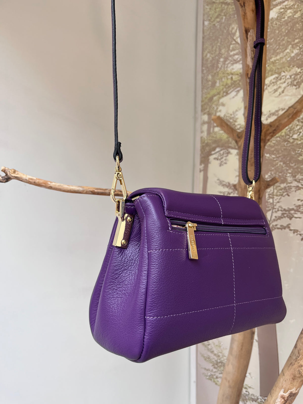 Violetinės spalvos elegantiška moteriška rankinė iš natūralios odos, su ilgu reguliuojamu ir nuimamu dirželiu, atvarto tipo užsegimu ir auksinės spalvos furnitūra. Rankinės nugarinėje pusėje yra išorinė kišenė su užtrauktuku, viduje – trys skyriai, iš kurių vidurinis užsegamas. Ši rankinė prancūziško dizaino, minimalistinio stiliaus, idealiai tinka nešioti tiek ant peties, tiek skersai per kūną – puikus pasirinkimas tiek kasdienai, tiek išeigai.
