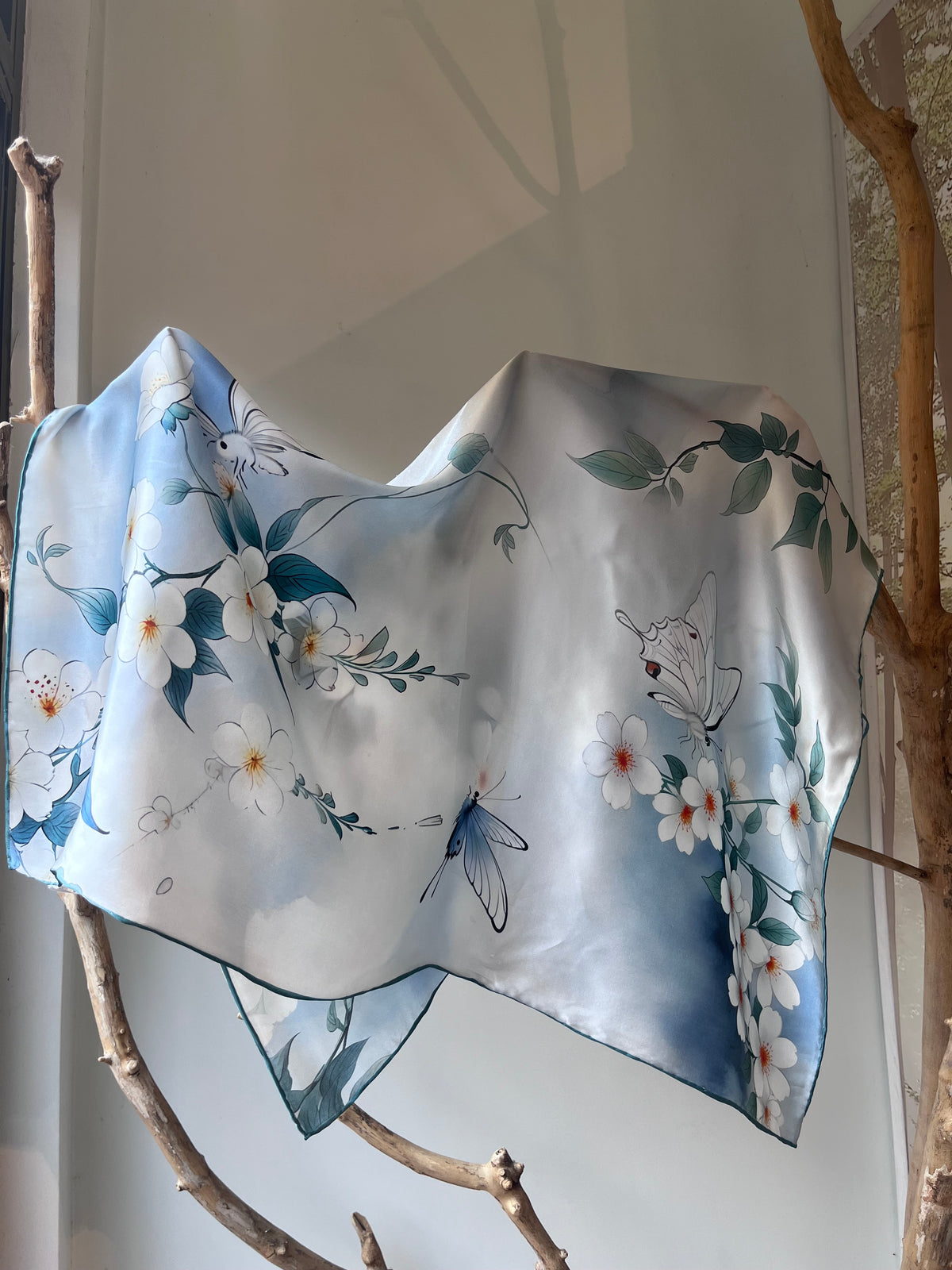 Blue silk scarf for women 90x90 cm with white floral and butterfly print, luxury square silk scarf in soft blue tones, romantic and elegant accessory for neck, hair or handbag, perfect gift, Mėlyna šilkinė skarelė moterims 90x90 cm su baltais žiedais ir drugeliais, prabangi kvadrato formos šilko skarelė švelnių mėlynų atspalvių, romantiškas ir elegantiškas aksesuaras kaklui, plaukams ar rankinei, subtili dovanos idėja moteriai.
