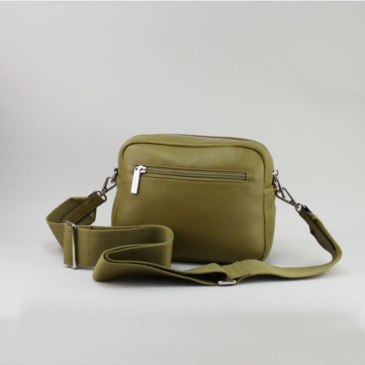 Back view of olive green leather handbag with rear zip pocket and detachable strap.
Žalsvai alyvuogių odinės rankinės nugarinė pusė su užtraukiama kišene ir nusegamu dirželiu.