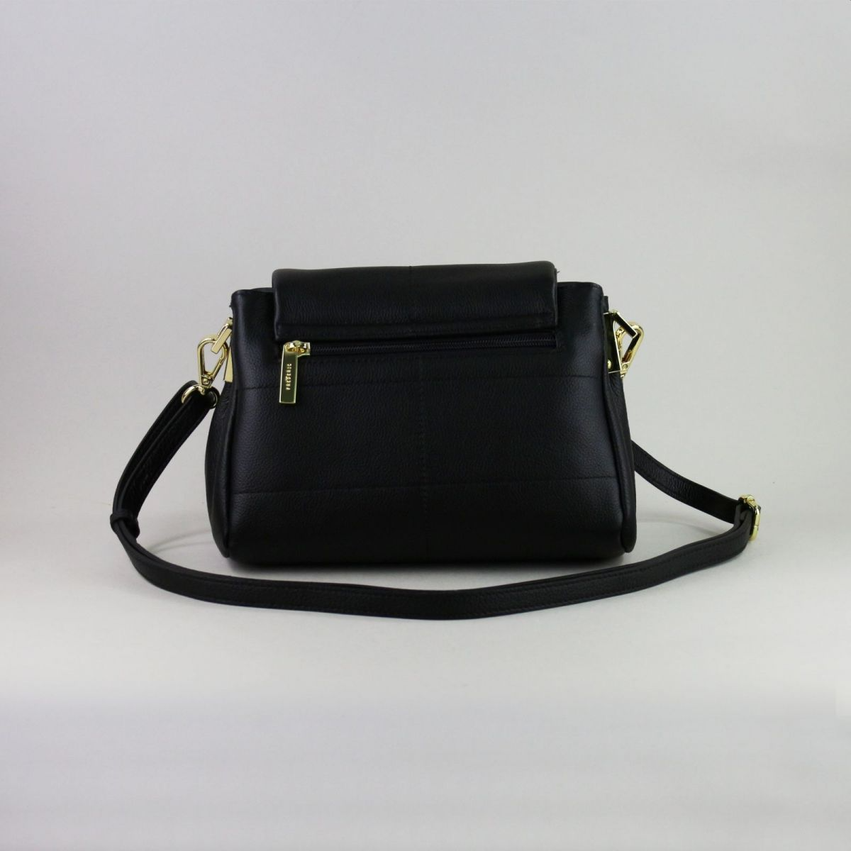 Black genuine leather handbag made by a reputable French manufacturer, featuring a structured flap closure, gold-tone hardware, rear zip pocket, and adjustable shoulder strap up to 115 cm. Elegant, compact, and timeless – a perfect accessory for daily use or evening outings. | Juoda natūralios odos rankinė, sukurta patikimo prancūzų gamintojo – su atvartu, auksine furnitūra ir reguliuojamu dirželiu – mėgstamas pasirinkimas stilingai moteriai.