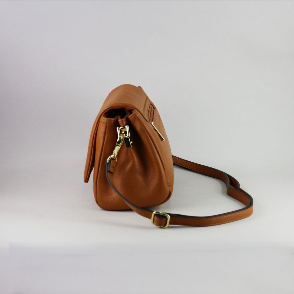 Caramel brown genuine leather handbag with flap closure, gold-tone hardware, adjustable shoulder strap (up to 115 cm), and exterior back zip pocket. Created by a trusted French manufacturer, this compact design is both elegant and practical – perfect for everyday or evening wear. | Karamelinės rudos spalvos natūralios odos rankinė su auksine furnitūra ir atvartu – stilingas ir mėgstamas modelis kasdienai ar išėjimui.

