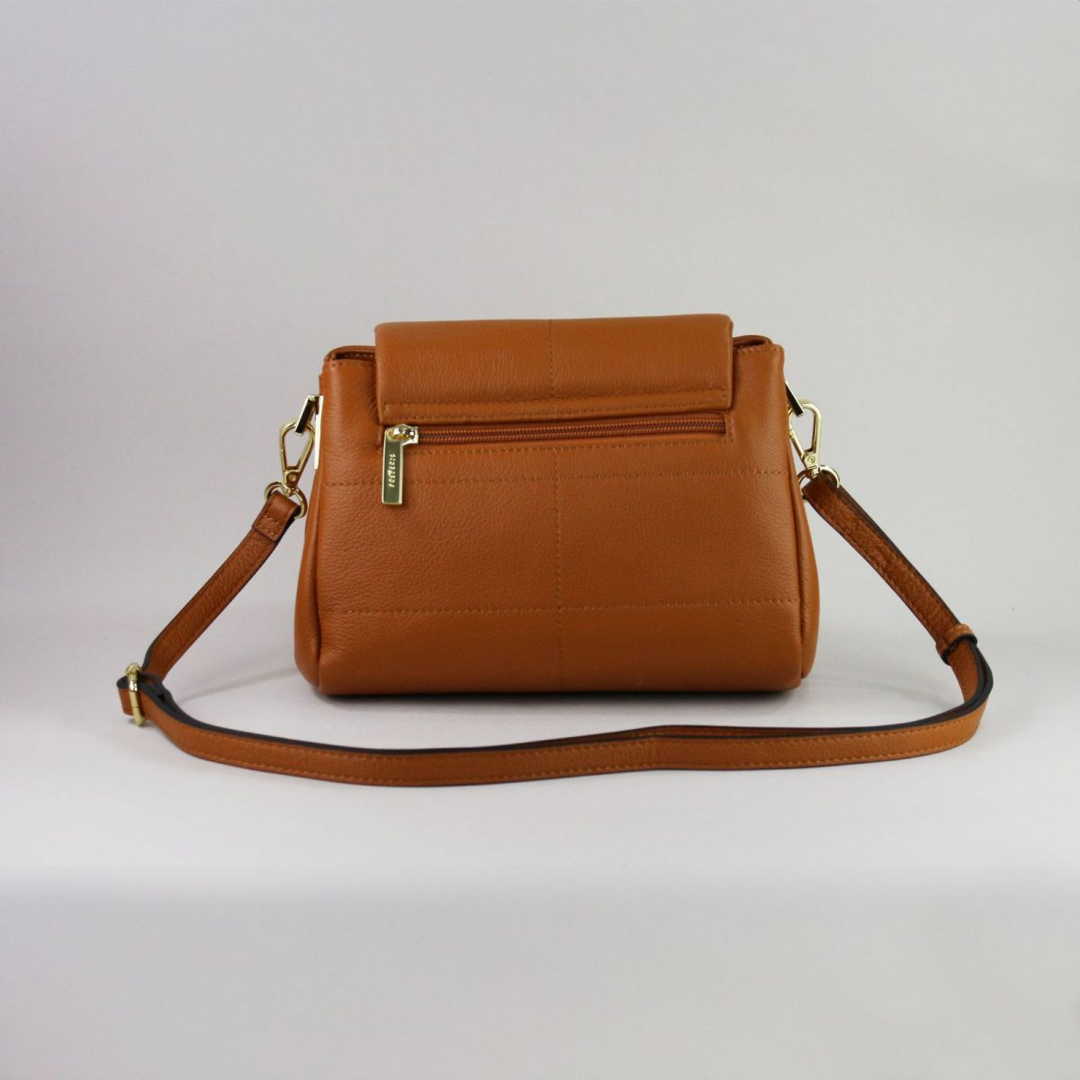 Caramel brown genuine leather handbag with flap closure, gold-tone hardware, adjustable shoulder strap (up to 115 cm), and exterior back zip pocket. Created by a trusted French manufacturer, this compact design is both elegant and practical – perfect for everyday or evening wear. | Karamelinės rudos spalvos natūralios odos rankinė su auksine furnitūra ir atvartu – stilingas ir mėgstamas modelis kasdienai ar išėjimui.


