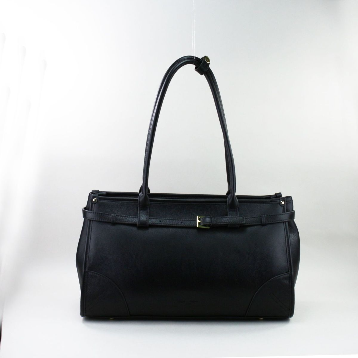 Elegant black genuine leather handbag from a new French collection, featuring long shoulder handles, golden hardware, a decorative belt detail, and a zipped back pocket. Ideal for everyday elegance and work or casual use. Juoda natūralios odos rankinė iš naujos kolekcijos – ilgos rankenos, auksinės detalės, klasikinis dizainas.