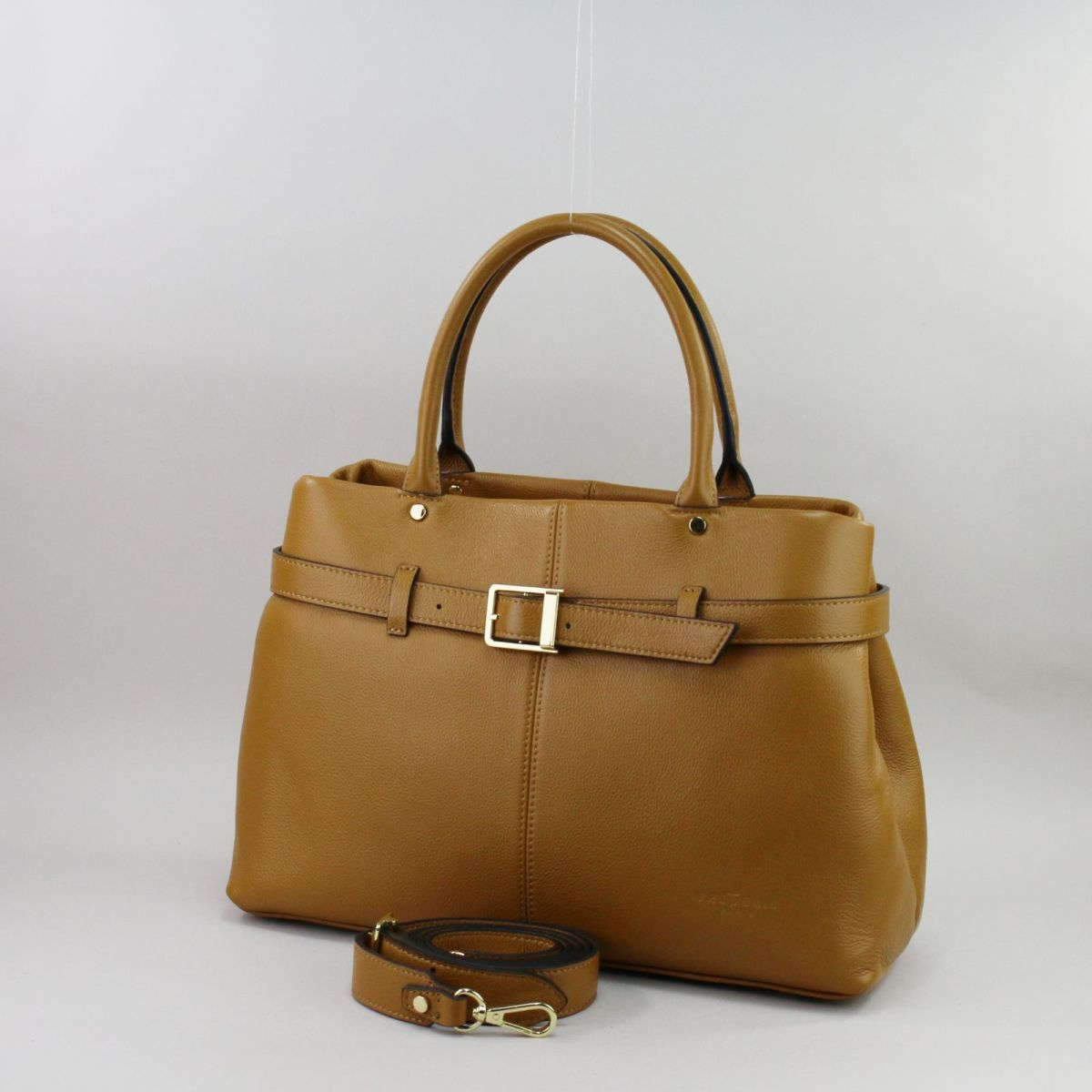 Camel color genuine leather handbag for women with elegant French design, short handles for shoulder wear, front buckle detail, and zip closure. Prancūziško dizaino natūralios odos rankinė moterims, šilta „camel“ spalva, dvigubos rankenos patogiam nešiojimui ant peties, užsegama užtrauktuku, priekyje dekoratyvinė sagtis.