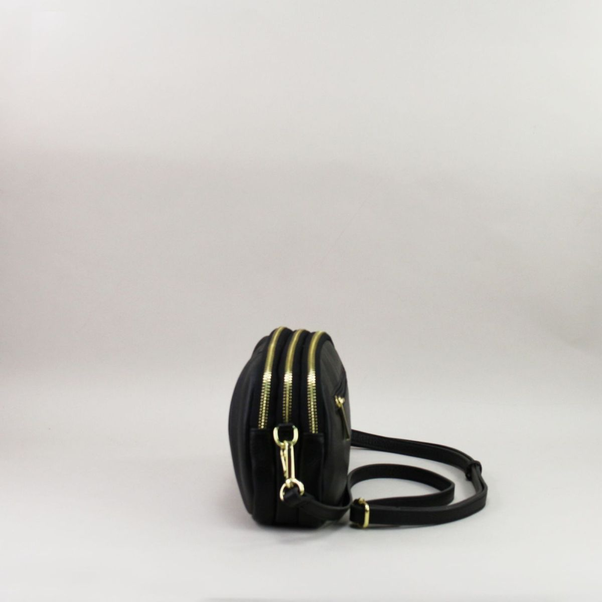 Side view of black leather handbag with double compartments and adjustable strap.
Juodos natūralios odos rankinės šoninis vaizdas su dviem skyriais ir reguliuojamu dirželiu.