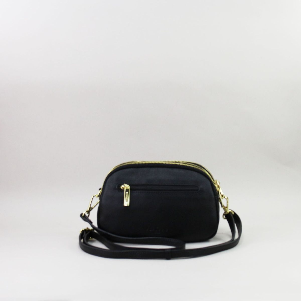 Back view of black leather handbag with rear zip pocket and elegant gold details.
 Juodos odinės rankinės nugarinė pusė su užtraukiama kišene ir elegantiškomis auksinėmis detalėmis.
