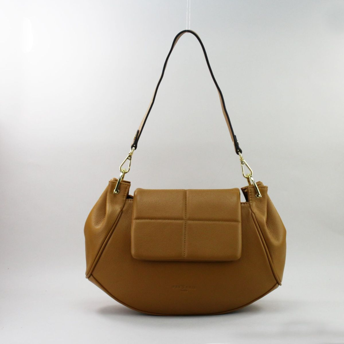 Elegant camel leather handbag with crescent silhouette and gold metal accents.
Elegantiška camel spalvos natūralios odos pusmėnulio formos rankinė su auksinėmis detalėmis.