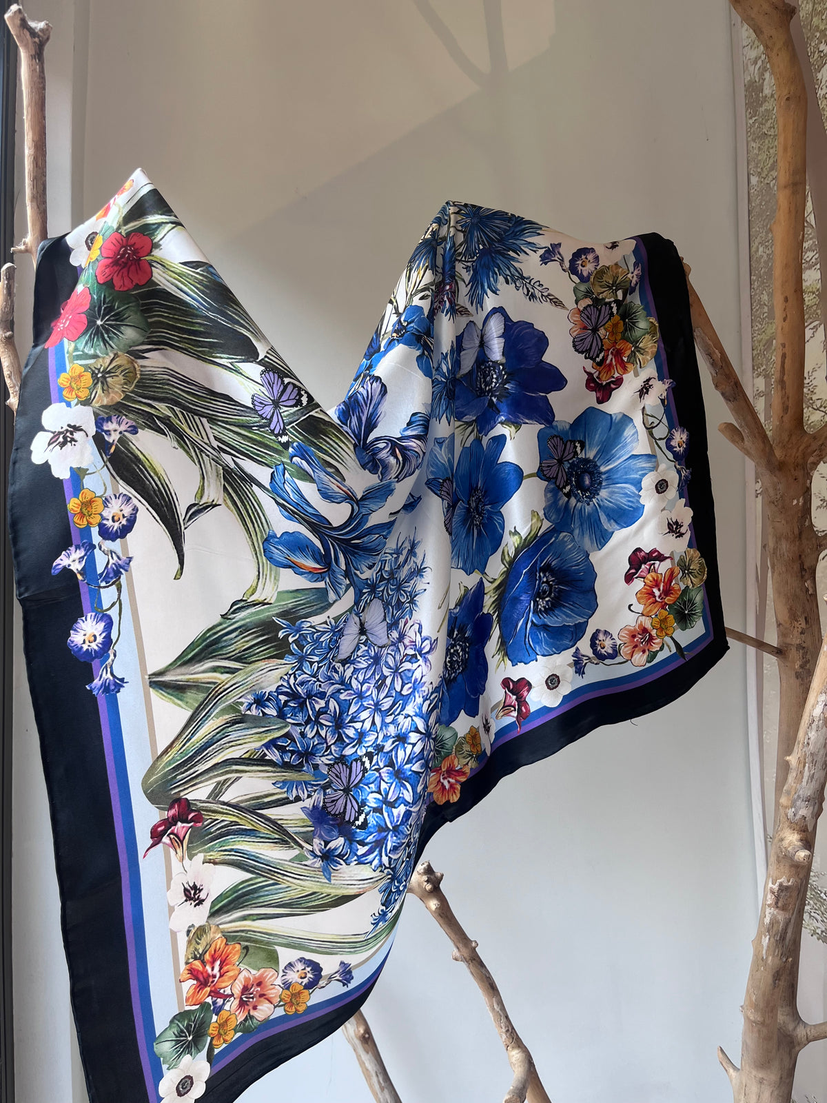 Silk scarf for women 90x90 cm with blue floral design, elegant square scarf with black border, luxury silk accessory for neck, hair or handbag, versatile scarf that changes look depending on how tied, Šilkinė skarelė moterims 90x90 cm su mėlynomis gėlėmis, elegantiška kvadratinė skarelė su juodu rėmeliu, prabangus šilko aksesuaras kaklui, plaukams ar rankinei, universalus aksesuaras, kuris atrodo skirtingai užrištas.