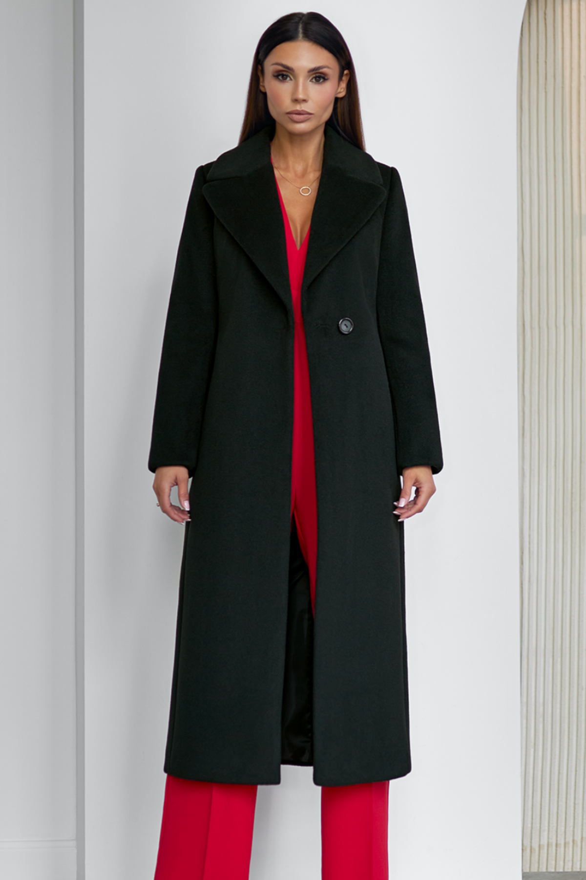 Black wool coat Amber for women – long classic winter coat with lapel collar, belt at the waist, side pockets and back vent. Elegant timeless design, insulated and lined, ideal for cold weather. Model is wearing size 34. Juodas vilnonis paltas Amber – klasikinis ilgas paltas su diržu, šoninėmis kišenėmis ir skeltuku nugaroje.