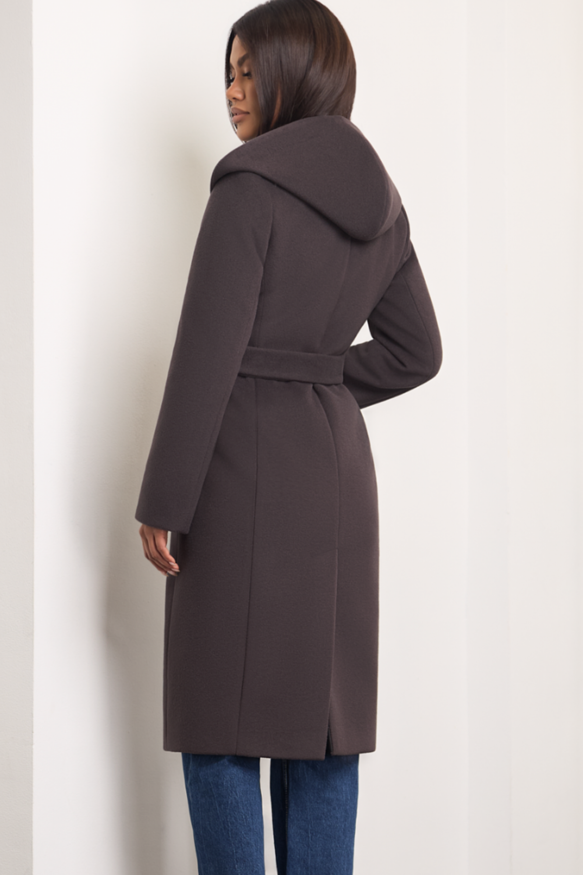 Brown espresso wool coat Zoe for women – long elegant winter coat with soft hood, belt at the waist, side pockets and back vent. Insulated and lined, warm and chic. Model is wearing size 34. Rudas vilnonis paltas Zoe – ilgas, šiltas paltas su kapišonu, diržu ir klasikinėmis detalėmis.
