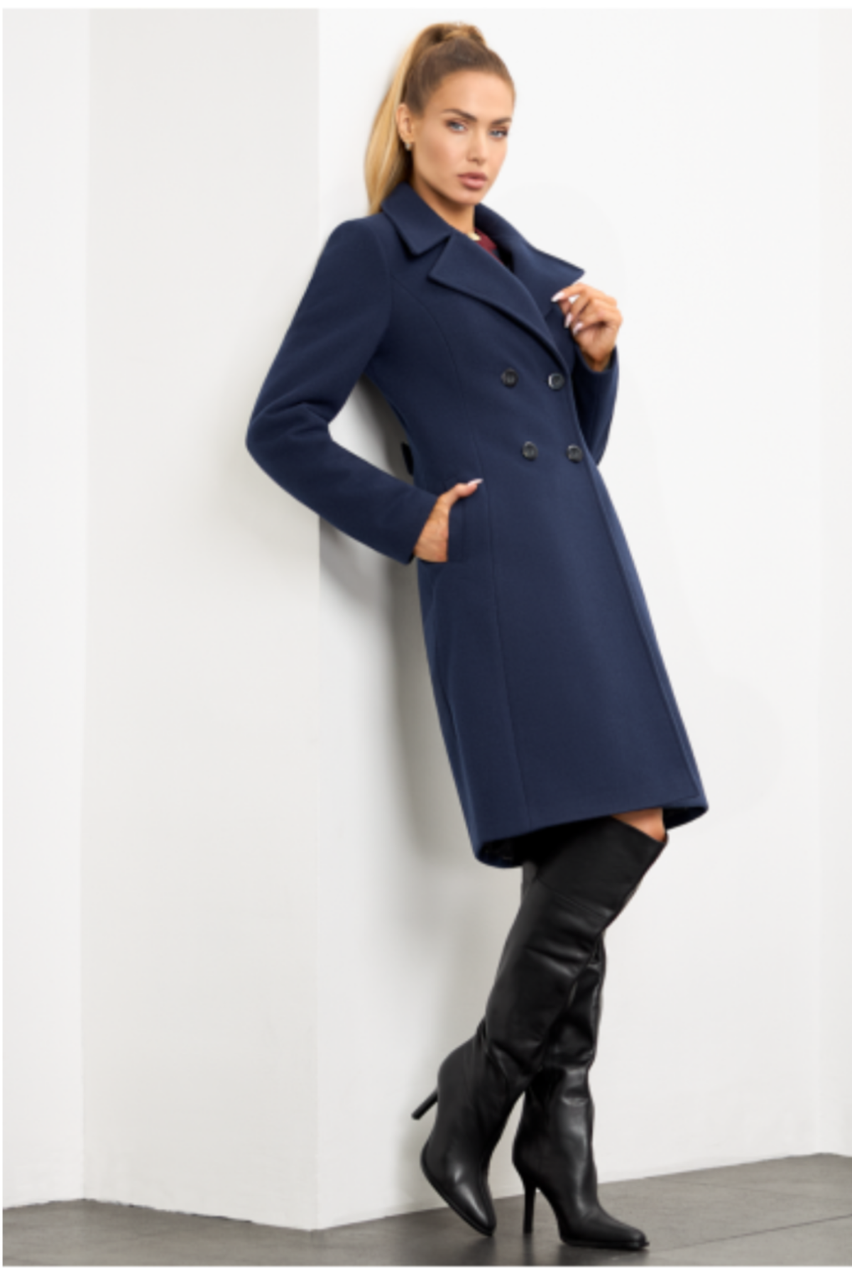 Navy blue wool coat Paris for women – elegant short knee-length coat with double-breasted buttons, wide lapel collar, back vent and decorative back tab. Insulated and lined, stylish and warm. Model is wearing size 34. Tamsiai mėlynas vilnonis paltas Paris – trumpas, klasikinis paltas su dvieile sagų eile ir nugara dekoruota patka.
