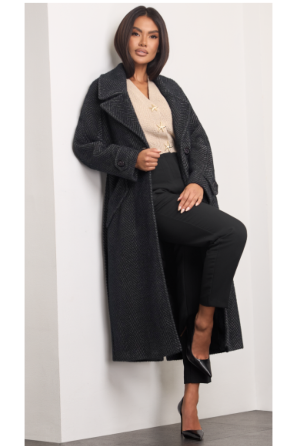 Nugat herringbone wool coat for women – long structured winter coat with double-breasted buttons, wide lapel collar, raglan sleeves, belt at the waist, flap pockets and back vent. Insulated and lined. Subtle mix of black and beige tones. Nugato spalvos moteriškas paltas su eglutės raštu – šiltas, ilgas, klasikinio silueto modelis.
