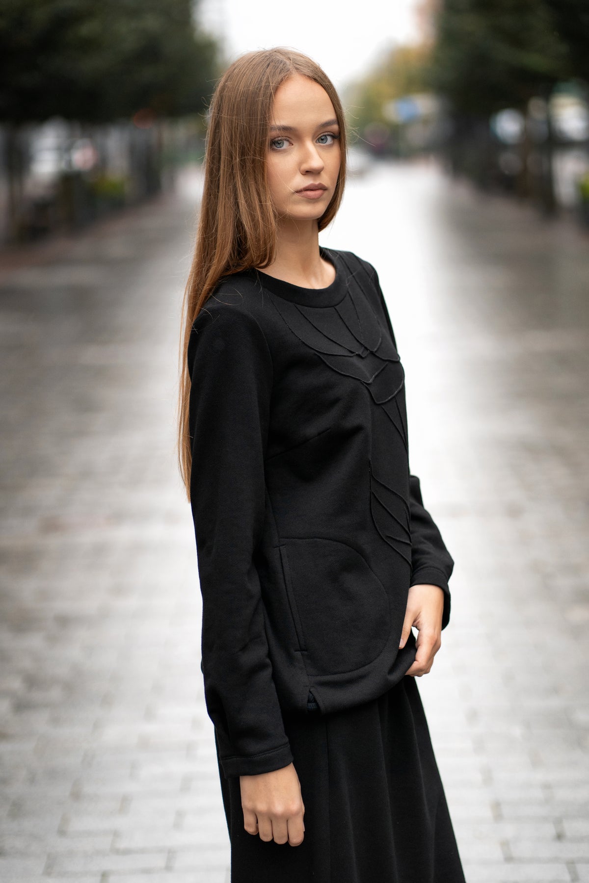 Džemperio priekio detalė su siuvinėta rože, tono prie tono siūlai, subtilus dekoras.
 Close-up of the embroidered rose detail on the front of the sweatshirt, tone-on-tone stitching for an elegant look.