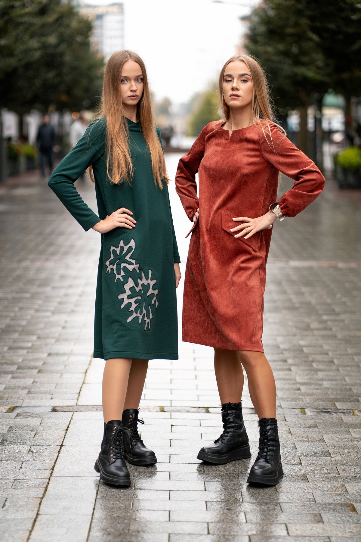 Woman wearing a terracotta velvet (corduroy) dress with long sleeves gathered at the cuffs, side pockets, and a subtle neckline detail. The dress is made from a soft cotton-based fabric with fine stripes. Mid-length, breathable and elegant design for autumn and winter. / Terakotos spalvos veliūrinė suknelė su kišenėmis ir subtiliu kaklo dizainu, iš medvilninio audinio su juostelėmis.