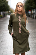 Woman wearing a moss green cotton dress with handmade tree branch embroidery on the front. The dress has long sleeves, side slits, pockets, and a straight silhouette. Comfortable medium-weight jersey fabric. / Moteris dėvi samaninės spalvos trikotažinę suknelę su rankų darbo medžio šakų dekoru, ilgomis rankovėmis, kišenėmis ir šoniniais skeltukais.