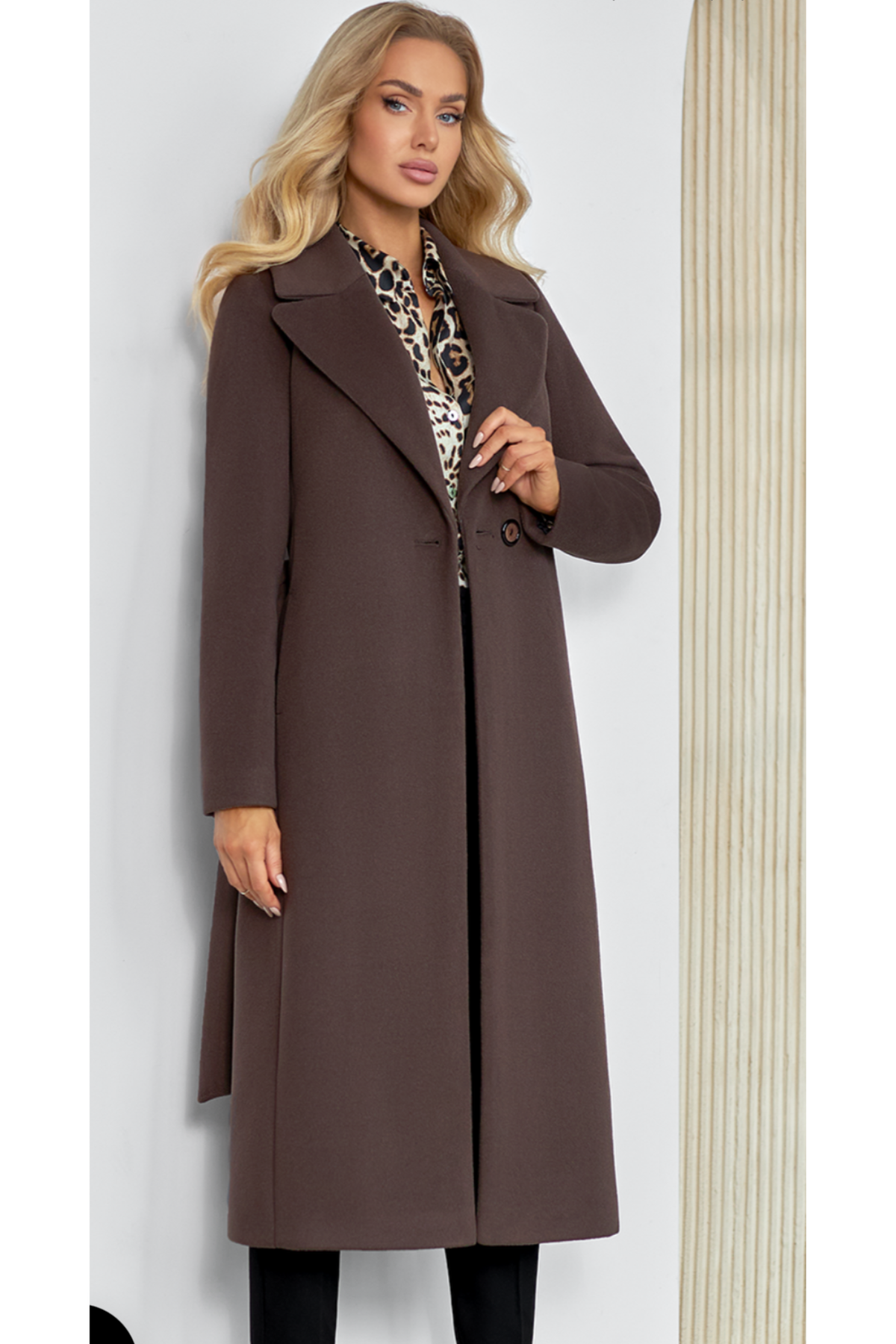 Classic chocolate wool coat for women – long elegant autumn and winter coat. Featuring a tailored silhouette with wide lapels, belt at the waist, side pockets and a back slit. Made from a warm wool-alpaca blend with high-quality lining. Model height 170 cm, wearing size 34. Klasikinis šokolado spalvos paltas moterims – elegantiškas ir šiltas pasirinkimas.