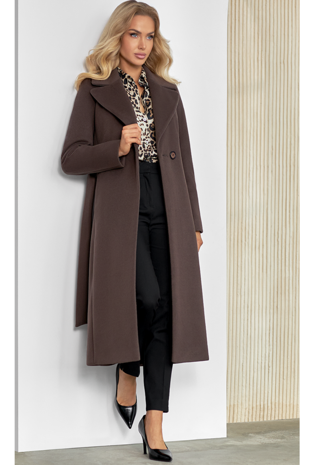 Classic chocolate wool coat for women – long elegant autumn and winter coat. Featuring a tailored silhouette with wide lapels, belt at the waist, side pockets and a back slit. Made from a warm wool-alpaca blend with high-quality lining. Model height 170 cm, wearing size 34. Klasikinis šokolado spalvos paltas moterims – elegantiškas ir šiltas pasirinkimas.