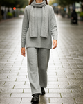 Elegant three-piece women’s knitted set made of soft cashmere-blend fabric, featuring a long scarf, relaxed dropped-shoulder sweater with side slits and cable-knit details, and wide straight-leg pants with a subtle side cable pattern. / Moteriškas trijų dalių megztas kostiumėlis iš švelnaus audinio su kašmyru: laisvai krintantis megztinis su nuleistais pečiais, pynių raštu ir skeltukais, tiesaus kritimo kelnės su pynute šone bei ilgas šalikas.