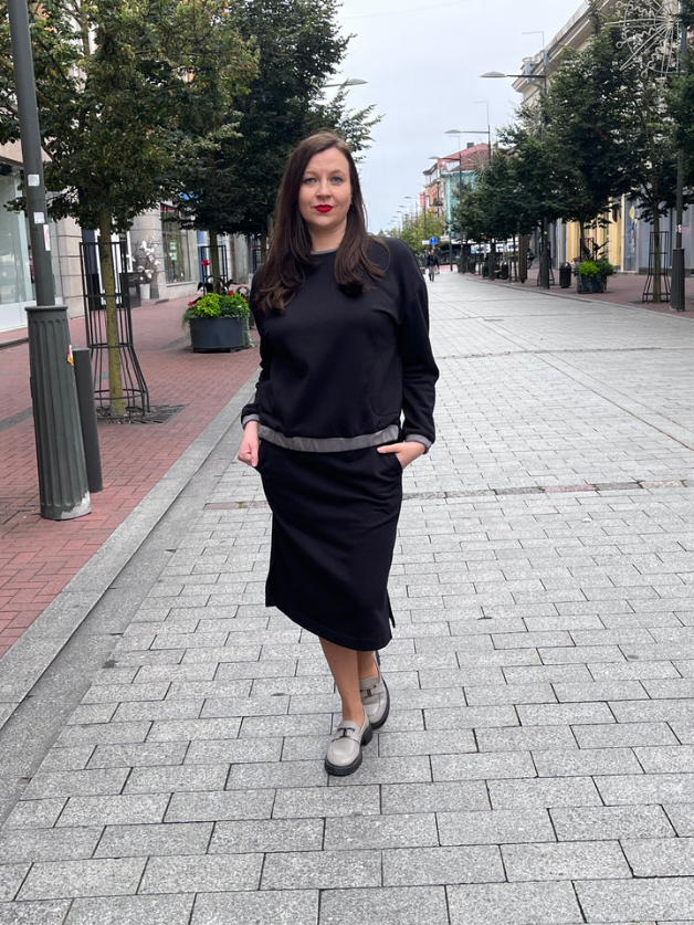 Moteriškas trikotažinis kostiumėlis: nuleistų pečių džemperis–palaidinė su kišenėmis ir tiesus sijonas su dviem skeltukais, elastingu juosmeniu; minkštas kvėpuojantis audinys, dydžiai 36–52, siūta Lietuvoje. / Women’s knit two-piece set with dropped-shoulder top and straight skirt with side slits, elastic waist; breathable cotton-rich fabric, sizes 36–52, made in Lithuania