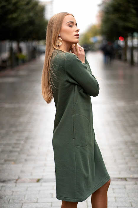 Green cotton-elastane midi dress for women with handmade dragonfly embroidery, bell silhouette and side pockets, designed and made in Lithuania. Comfortable and elegant knitwear dress perfect for autumn and winter season. Žalia trikotažinė suknelė moterims su rankų darbo laumžirgio siuviniu, varpelio siluetu ir kišenėmis – pagaminta Lietuvoje