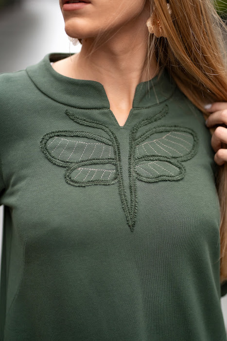 Green cotton-elastane midi dress for women with handmade dragonfly embroidery, bell silhouette and side pockets, designed and made in Lithuania. Comfortable and elegant knitwear dress perfect for autumn and winter season. Žalia trikotažinė suknelė moterims su rankų darbo laumžirgio siuviniu, varpelio siluetu ir kišenėmis – pagaminta Lietuvoje