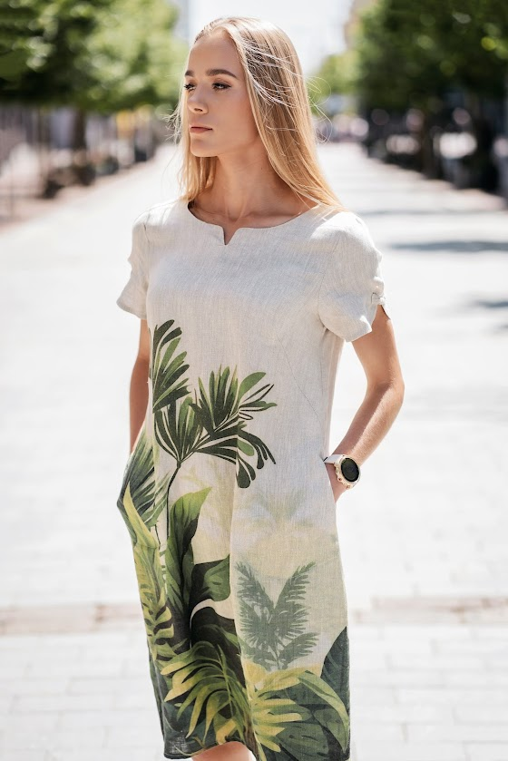 Model wearing a natural linen dress with a relaxed silhouette and side pockets, made from softened linen fabric, perfect for warm summer days. The model is 173 cm tall and wears size 40. Suknelė pasiūta Lietuvoje iš 100 % lino – lengva, elegantiška ir kvėpuojanti.