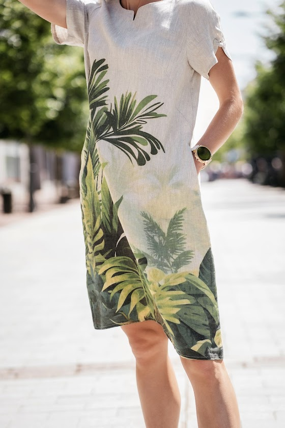 Model wearing a natural linen dress with a relaxed silhouette and side pockets, made from softened linen fabric, perfect for warm summer days. The model is 173 cm tall and wears size 40. Suknelė pasiūta Lietuvoje iš 100 % lino – lengva, elegantiška ir kvėpuojanti.