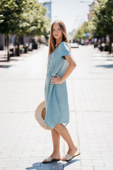 Pastel mint linen summer dress for women with extended corners and side pockets, ideal for warm weather. Model is 173 cm tall and wears size 38. The dress has a relaxed fit, short sleeves (23–24 cm), and a gently flowing silhouette, length 102–108 cm depending on size. Perfect for natural comfort and elegance. – Pastelinės mėtos spalvos lininė vasaros suknelė moterims su kampuotais prailginimais ir šoninėmis kišenėmis. Modelio ūgis – 173 cm, dėvi 38 dydį. Suknelė laisvo kirpimo, trumpomis rankovėmis (23–24 