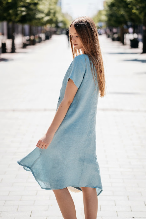 Pastel mint linen summer dress for women with extended corners and side pockets, ideal for warm weather. Model is 173 cm tall and wears size 38. The dress has a relaxed fit, short sleeves (23–24 cm), and a gently flowing silhouette, length 102–108 cm depending on size. Perfect for natural comfort and elegance. – Pastelinės mėtos spalvos lininė vasaros suknelė moterims su kampuotais prailginimais ir šoninėmis kišenėmis. Modelio ūgis – 173 cm, dėvi 38 dydį. Suknelė laisvo kirpimo, trumpomis rankovėmis (23–24 