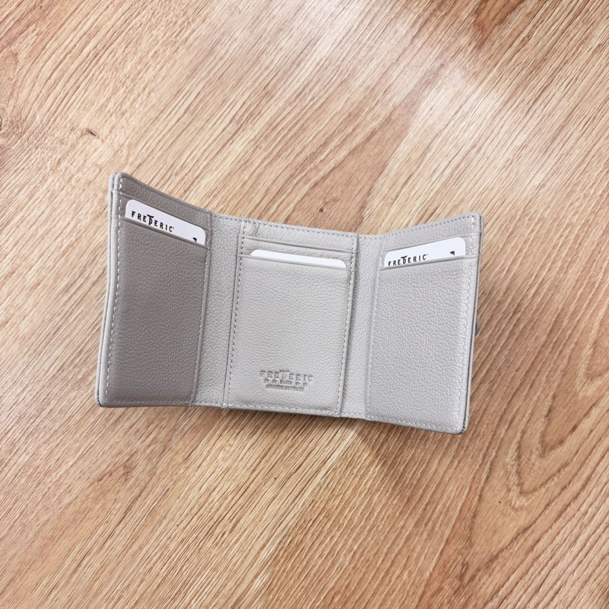 Elegantiška pilka moteriška piniginė iš natūralios odos su auksinės spalvos furnitūra ir užsegimu. Kompaktiškas dydis 8x10x2,5 cm leidžia patogiai laikyti pinigus visu ilgiu, dokumentus, banko bei nuolaidų korteles. Monetoms skirtas skyrelis su užtrauktuku suteikia papildomo patogumo. Piniginė yra maža, bet labai talpi, todėl lengvai telpa net ir mažoje rankinėje. Tai stilingas, praktiškas ir ilgaamžis aksesuaras, puikiai tinkantis kasdieniam naudojimui ar kaip dovanų idėja.