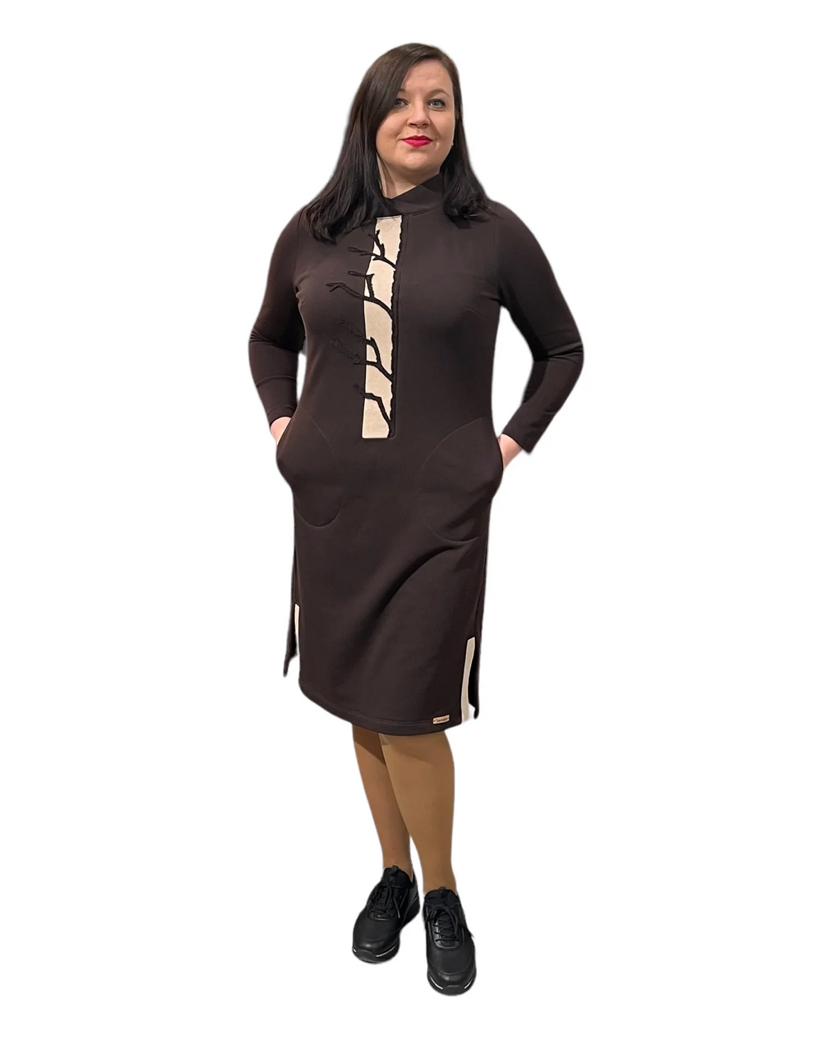 Woman wearing a moss green cotton dress with handmade tree branch embroidery on the front. The dress has long sleeves, side slits, pockets, and a straight silhouette. Comfortable medium-weight jersey fabric. / Moteris dėvi šokoladinės spalvos trikotažinę suknelę su rankų darbo medžio šakų dekoru, ilgomis rankovėmis, kišenėmis ir šoniniais skeltukais.